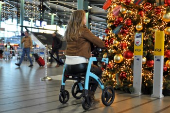 Young lady in airport sitting in a rollator