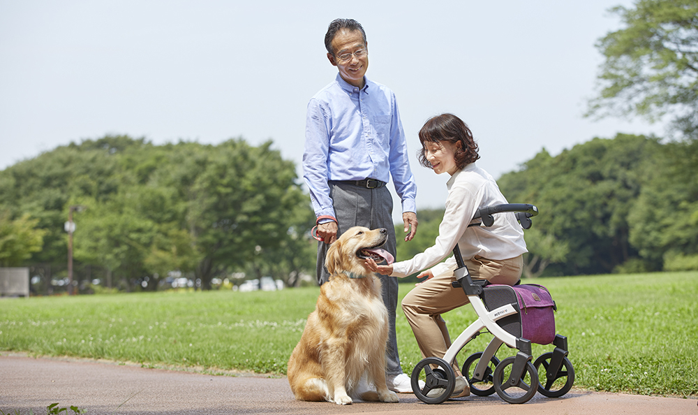 Woman sitting on a Rollz Flex rollator and petting a dog