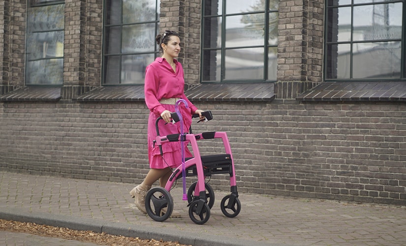 Girl walking with a pink rollator while having mobility issues